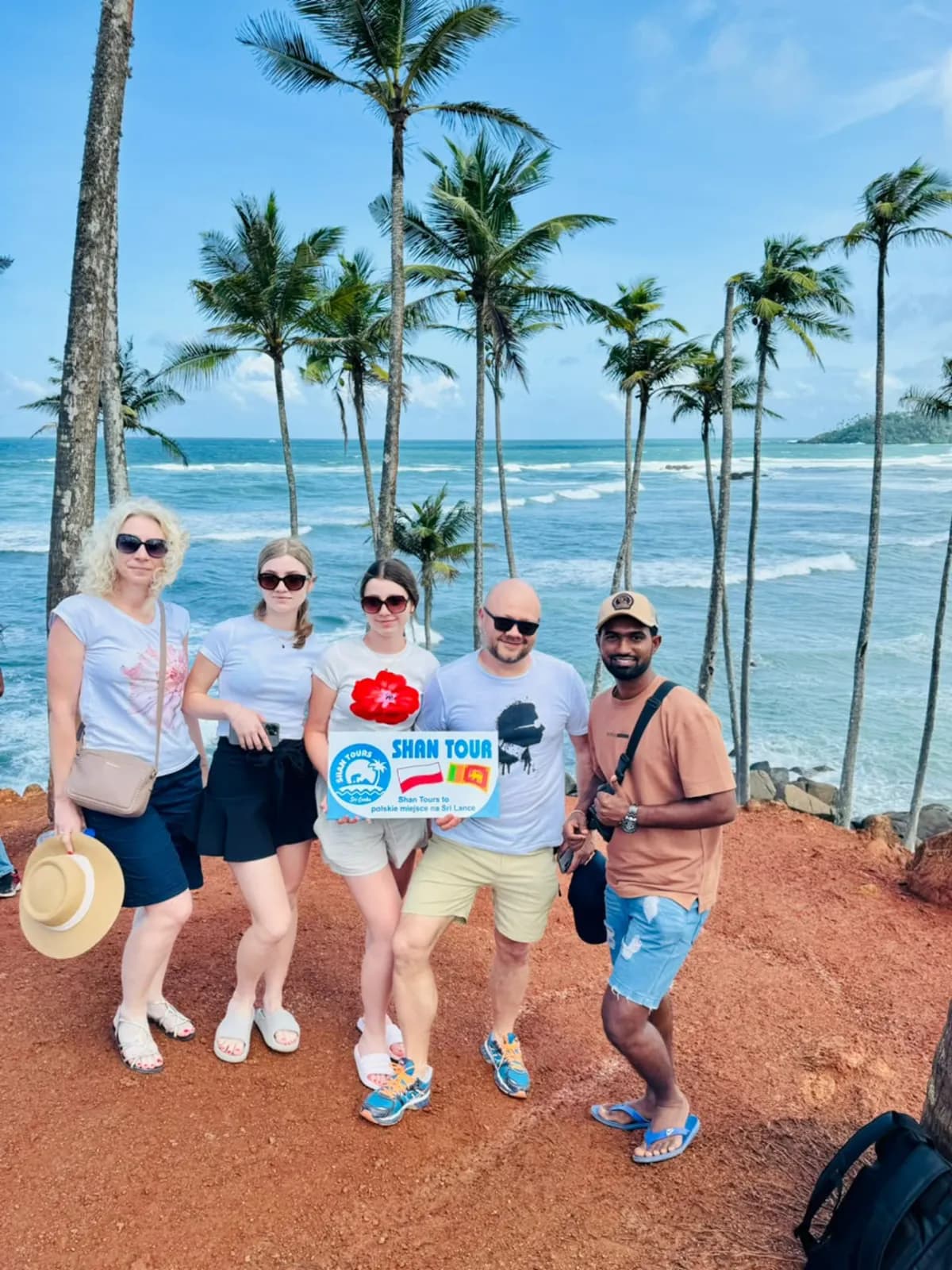 A group of travellers at a palm-lined viewpoint above the southern coast