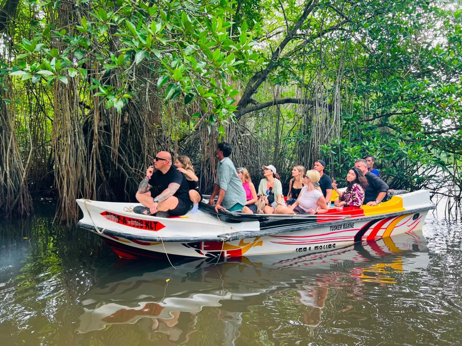 A boat of travellers gliding through a mangrove channel